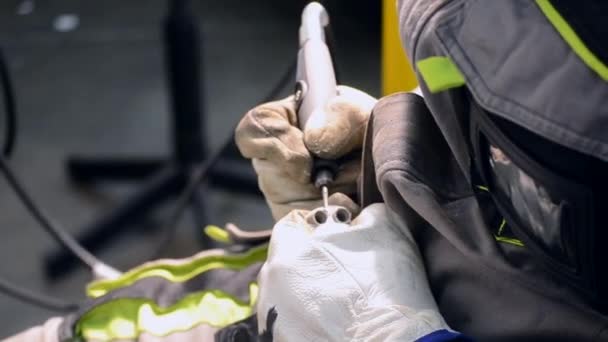 De man in uniform slijpt metalen details met de hand close-up. Detail van het slijpmetaal — Stockvideo