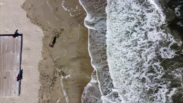 Persone che camminano e si rilassano sulla spiaggia nella giornata di sole. Volo aereo con vista drone — Video Stock