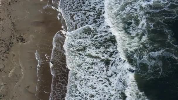 Політ повітряного дрона над красивими морськими хвилями на піщаному пляжі з білою піною — стокове відео