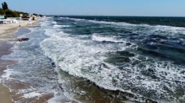 İnsanlar güneşli bir günde sahilde yürüyüp dinleniyorlar. Hava Aracı Görünümü Uçuşu