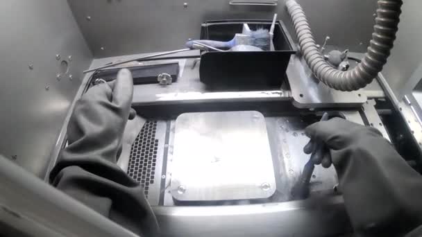 Pekerja laki-laki di sarung tangan karet membersihkan platform pencetakan di dalam printer 3d untuk logam — Stok Video