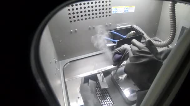 Работник в резиновых перчатках чистит печатную платформу внутри 3D принтера для металла — стоковое видео