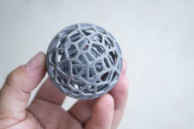 Podyum tozundan çıkan 3D yazıcıya basılmış plastik model tutan adam.