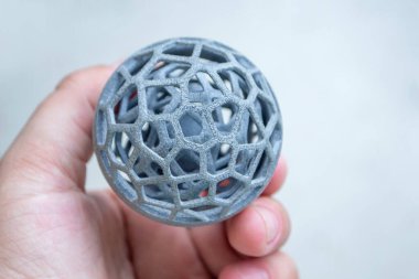 Podyum tozundan çıkan 3D yazıcıya basılmış plastik model tutan adam.