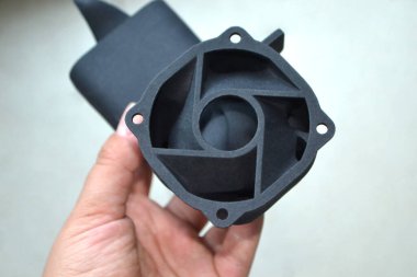 Podyum tozundan çıkan 3D yazıcıya basılmış plastik model tutan adam. Çoklu Jet Füzyon MJF.