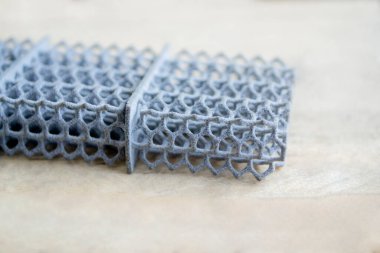 Toz poliyamide ait 3D yazıcıya basılmış bir nesne. Gri nesne termal yazdırma başlığı altında oluştu.