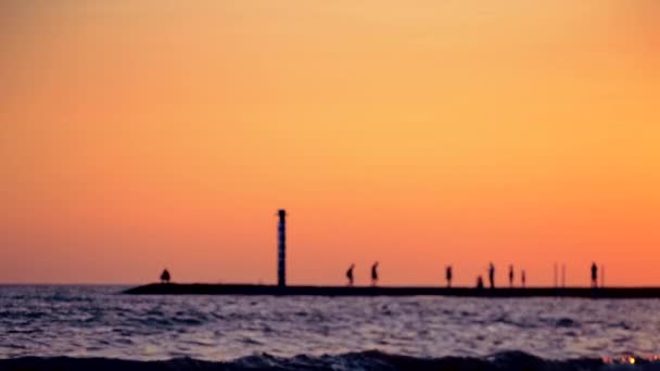 Black silhouette of pier with flashing beacon and walking people — Stock Video