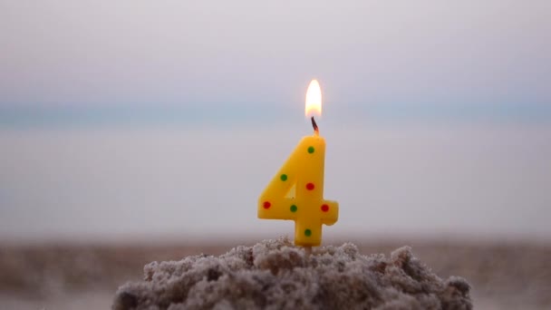 Candle number four inserted sand and burns. Lighted candle in sand on background — Stockvideo