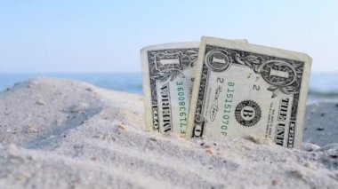 Güneşli yaz gününde, deniz mavisi gökyüzünün arka planında kumdaki iki dolarlık banknot..