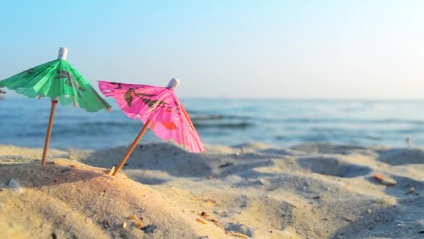 Paper cocktail multi-colored umbrellas on sandy sea beach on sunny summer day — Stock videók