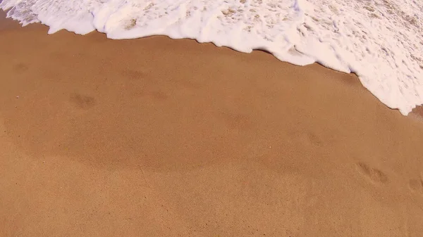 Havsvåg med vitt skum rullar över sandstranden. Ovanifrån. — Stockfoto
