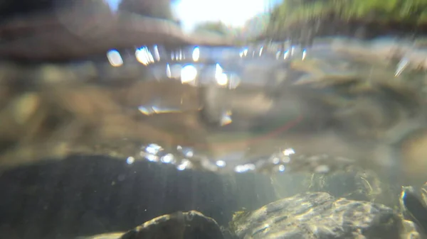 흐르는 물, 물을 통한 태양의 스카이라이트, 바닥에 놓인 돌들 — 스톡 사진