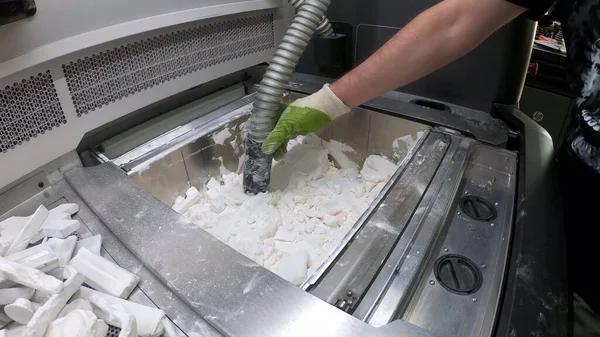 Homme nettoie les détails imprimés sur une imprimante 3D industrielle de la poudre plastique blanche — Photo