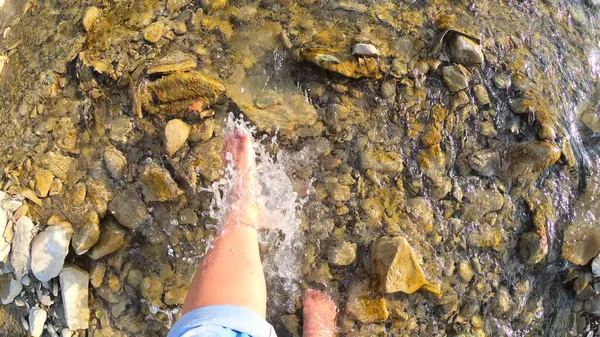 소녀는 햇볕이 잘 드는 여름에 얕은 강의 돌 위에 발로 물을 뿌린다 — 스톡 사진