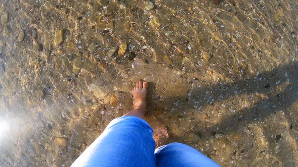 Menina caminha descalça em um fundo arenoso com pedras da costa do mar — Fotografia de Stock