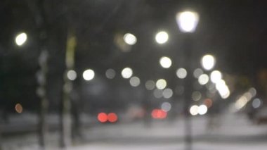 Şehir manzaralı ışıklar, yağan kar, gece caddesi, arabaların farları.