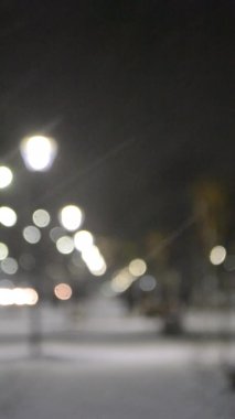 Şehir manzaralı ışıklar, yağan kar, gece caddesi, arabaların farları.