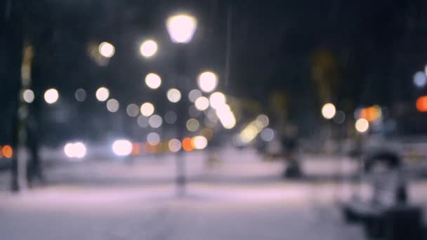 Luzes da vista da cidade, neve caindo, rua noturna, pontos bokeh de faróis de carros — Vídeo de Stock