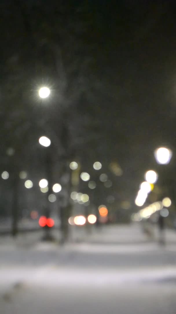 City view lichten, vallende sneeuw, nacht straat, bokeh vlekken van koplampen van auto 's — Stockvideo