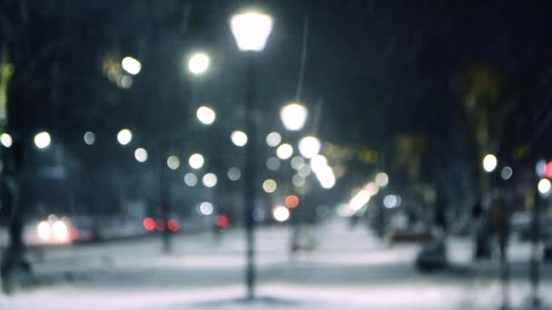 Stadsutsikt ljus, fallande snö, natt gata, bokeh fläckar av strålkastare i bilar — Stockvideo
