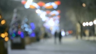 Arka plan bulanık. Kış gecesi kar yağarken şehir caddesi.
