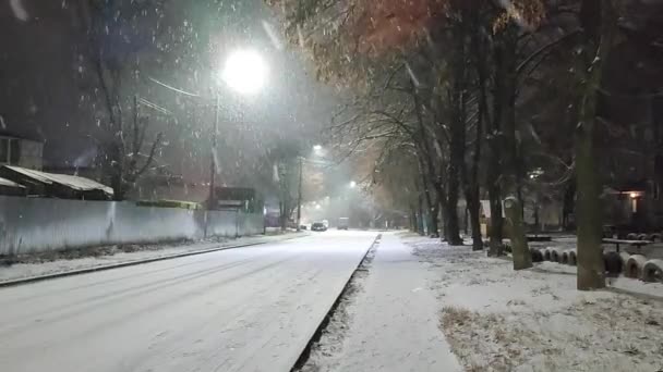 Kış gecesi şehir caddesinde kar yağışı manzarası. — Stok video