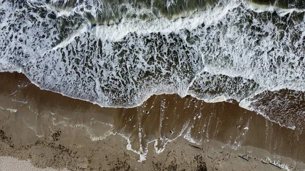 Avión teledirigido vuelo sobre las olas del mar que rodar sobre la orilla arenosa. —  Fotos de Stock