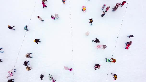 Vista superior de pessoas patinando em uma grande pista de gelo ao ar livre em um dia de inverno. — Vídeo de Stock