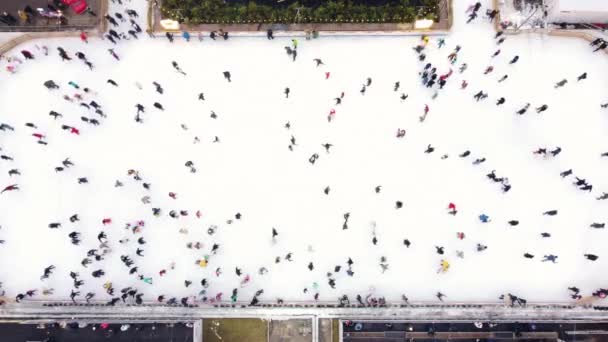 Blick von oben auf Menschen, die an einem Wintertag auf einer großen Open-Air-Eisbahn Schlittschuh laufen. — Stockvideo