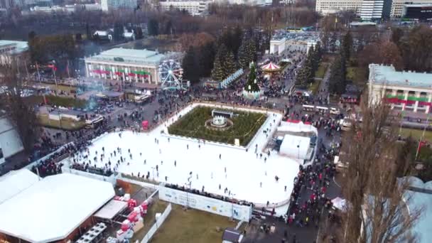 Aerial panoramic view cityscape urban park outdoor ice skating rink, many people — Stock Video