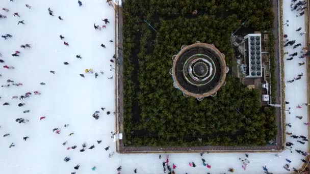 Drohnenblick über viele Menschen, die im Winter auf einer Eisbahn unter freiem Himmel Schlittschuh laufen. — Stockvideo