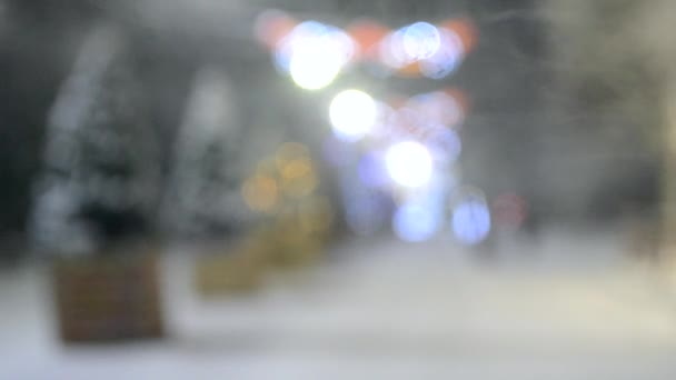 Wazig achtergrond van besneeuwde stad straat met kerstbomen en verlichting — Stockvideo