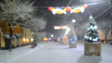 Yılbaşı ağaçları ve aydınlatma ile karlı şehir sokağının bulanık arka planı