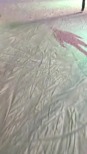 Gente patinando en una pista de patinaje sobre hielo con luz colorida al aire libre en invierno — Vídeos de Stock