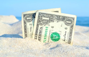 Güneşli yaz aylarında deniz mavisi gökyüzünün arka planında kumdaki iki dolarlık banknot.