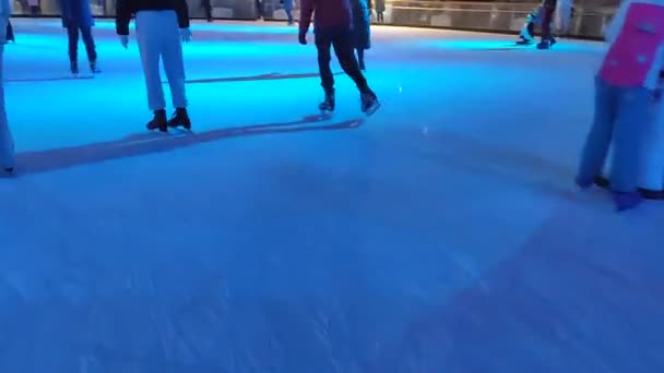 Folk som skøyter på en skøytebane med fargerikt lys om vinteren. – stockvideo
