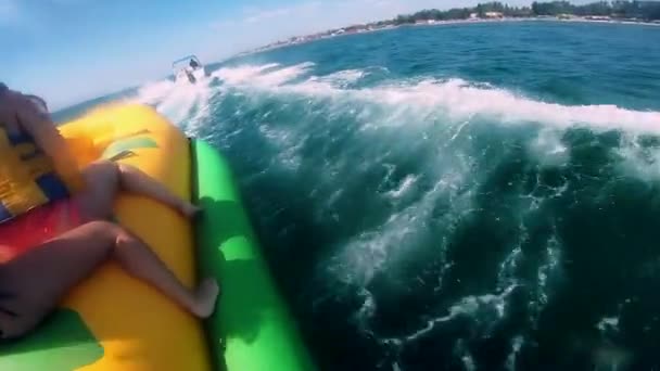 La gente que monta en la atracción inflable del agua con el barco a motor plátano en el mar — Vídeos de Stock