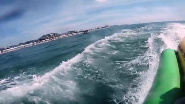 La gente que monta en la atracción inflable del agua con el barco a motor plátano en el mar — Vídeo de stock