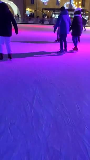 Les gens patinent sur une patinoire avec une lumière colorée en plein air en hiver — Video