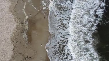 Üzerinde beyaz köpük olan deniz dalgaları. Kumlu sahilde güzel deniz manzarası dalgaları