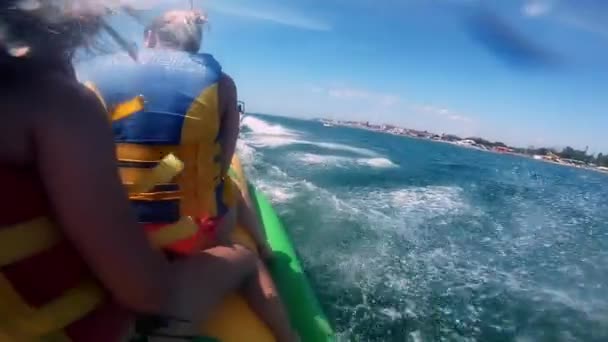 Люди, катающиеся на водных надувных аттракционах с моторной лодкой Банан на море — стоковое видео