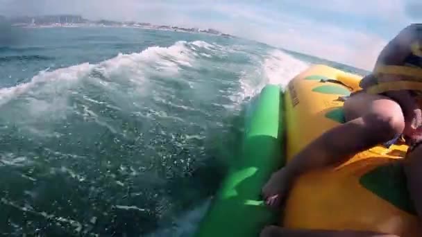 La gente que monta en la atracción inflable del agua con el barco a motor plátano en el mar — Vídeos de Stock