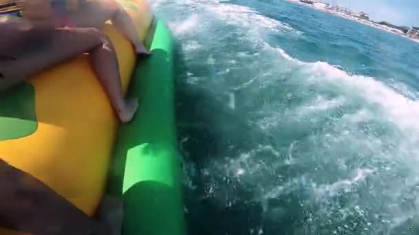 Persone che cavalcano sull'acqua attrazione gonfiabile con barca a motore Banana in mare — Video Stock