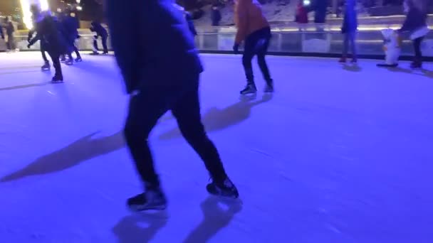 Pessoas patinando em uma pista de patinação no gelo com luz colorida ao ar livre no inverno — Vídeo de Stock