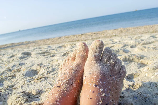 Dos pies desnudos de mujer caucásica manchada de arena con roca de concha en el mar arenoso —  Fotos de Stock