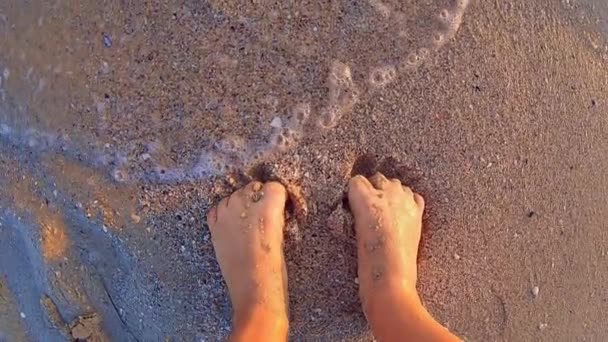 Mädchen mit nackten Füßen wühlen im nassen Sand des Strandes am Strand bei Sonnenuntergang