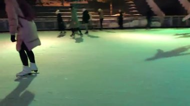 İnsanlar kış aylarında açık havada renkli ışıkla buz pateni pistinde kayıyorlar.