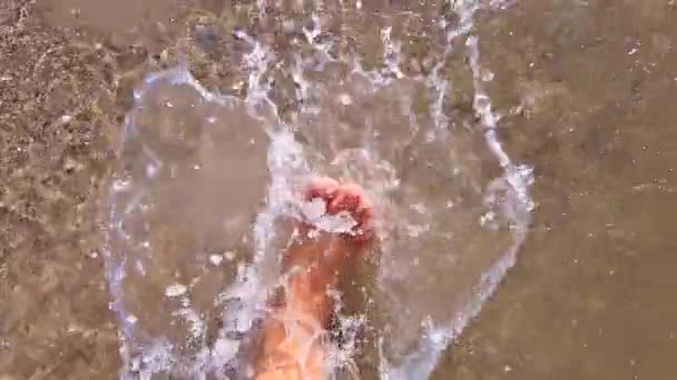 Menina com os pés descalços andando na água na praia de areia do mar e espirra água — Vídeo de Stock