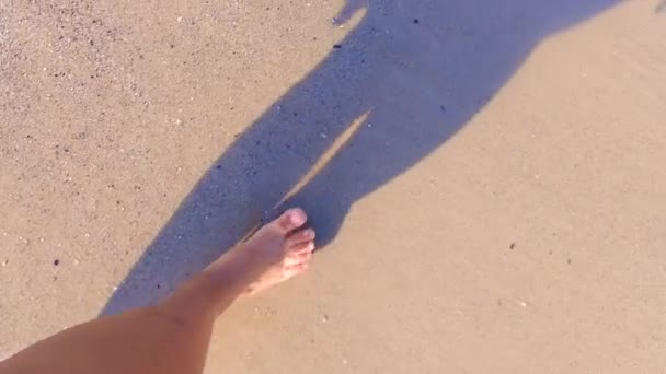 Chica con los pies desnudos caminando sobre el agua en la playa de arena de mar y salpicaduras de agua — Vídeo de stock