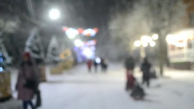Yılbaşı ağaçları ve aydınlatma ile karlı şehir sokağının bulanık arka planı
